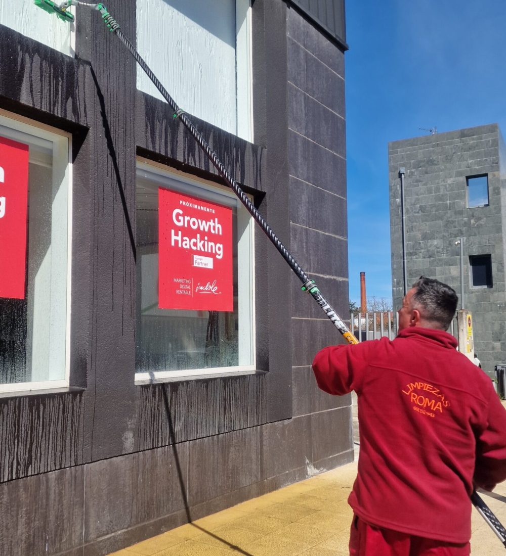 Empleado de Limpiezas Roma limpiando cristales en la oficina de Índole Digital en Cantabria